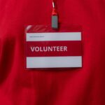 A close-up of a volunteer name tag hanging on a red lanyard, symbolizing community service.